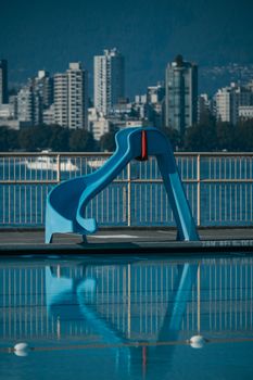 A vibrant cityscape featuring a blue slide by a swimming pool in Vancouver.