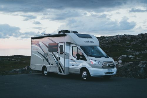 Free A sleek RV parked at dusk in a scenic natural landscape with rocky terrain. Stock Photo