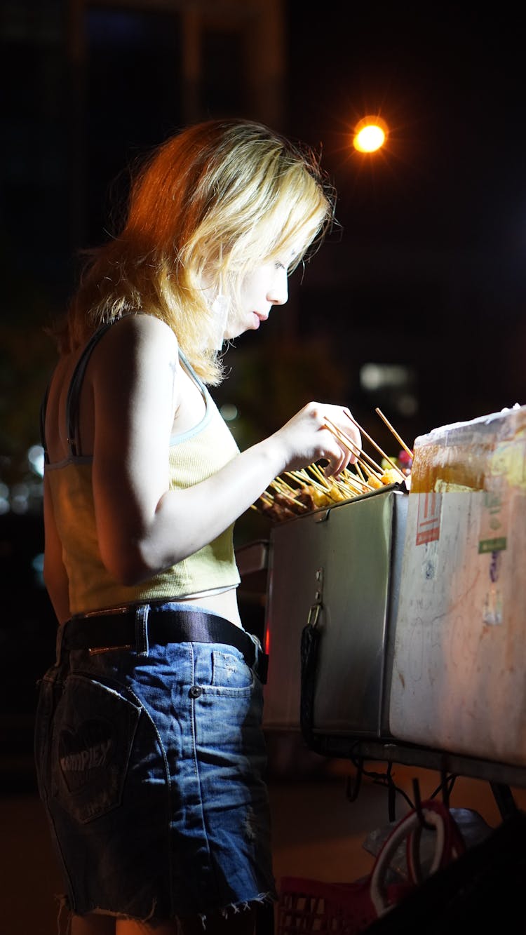 A Woman In A Tank Top Buying Street Foods