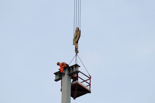 Free A construction worker operates at high altitude using a crane on a clear day. Stock Photo