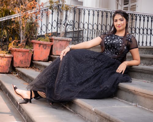 Free A Woman in Black Dress Sitting on Concrete Stairs Stock Photo
