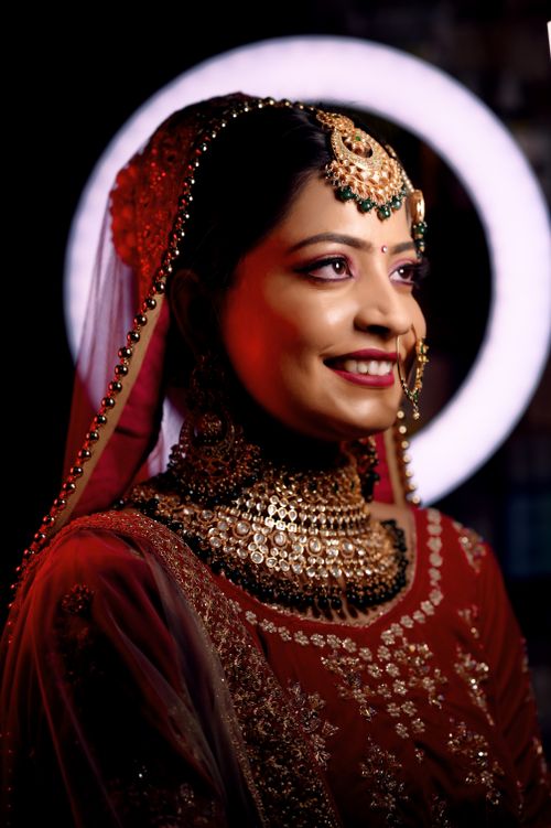 Free Elegant Indian bride adorned in traditional red and gold jewelry with artistic makeup. Stock Photo
