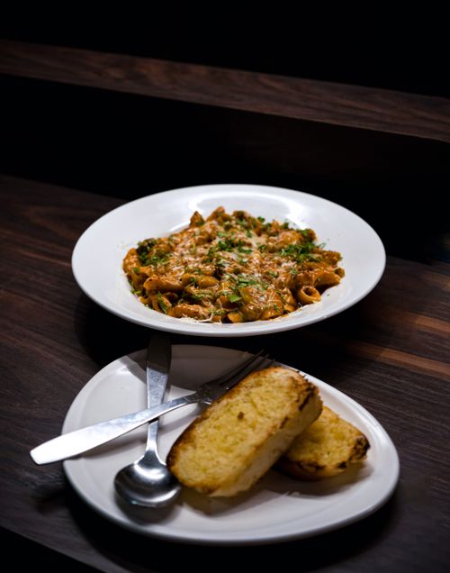 Free Delicious pasta served with garlic bread on a dark wooden table, perfect for food lovers. Stock Photo
