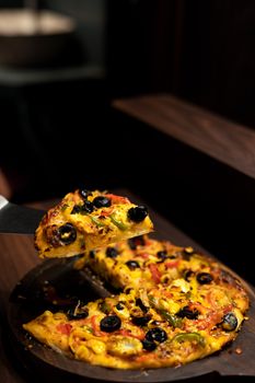 Delicious pizza slice with olives, peppers, and cheese, perfect for food enthusiasts.