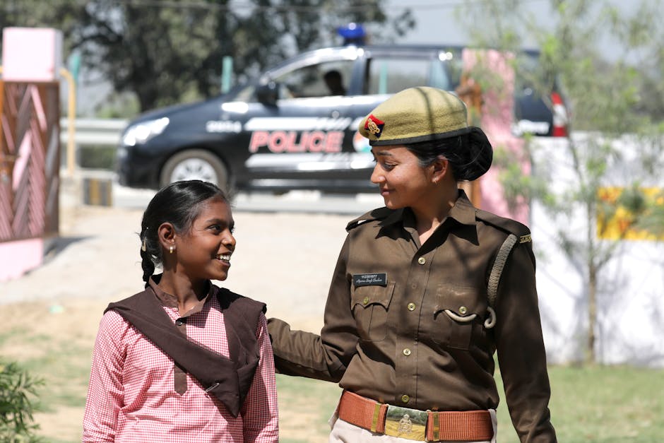 A friendly police officer interacts with a smiling child outdoors, indicating safety and community relations.