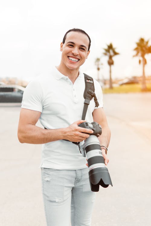 Fotografi Fokus Dangkal Pria Yang Berdiri Sambil Memegang Kamera Dslr