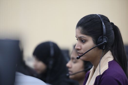 Young Asian woman working attentively as a call center agent in an office environment.