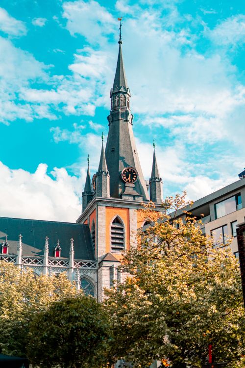 Free Captivating view of a church spire against a vibrant blue sky in Liège, Belgium. Stock Photo