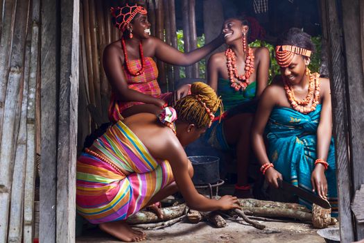 A vibrant scene of African women dressed in traditional attire, joyfully preparing a meal outdoors.