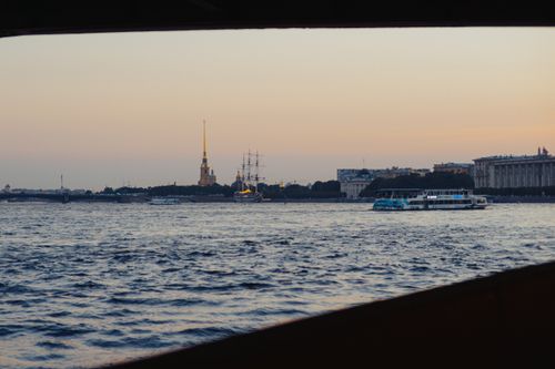 Free Ferry boat on a river with a cityscape at dusk, capturing the serene water and architectural backdrop. Stock Photo