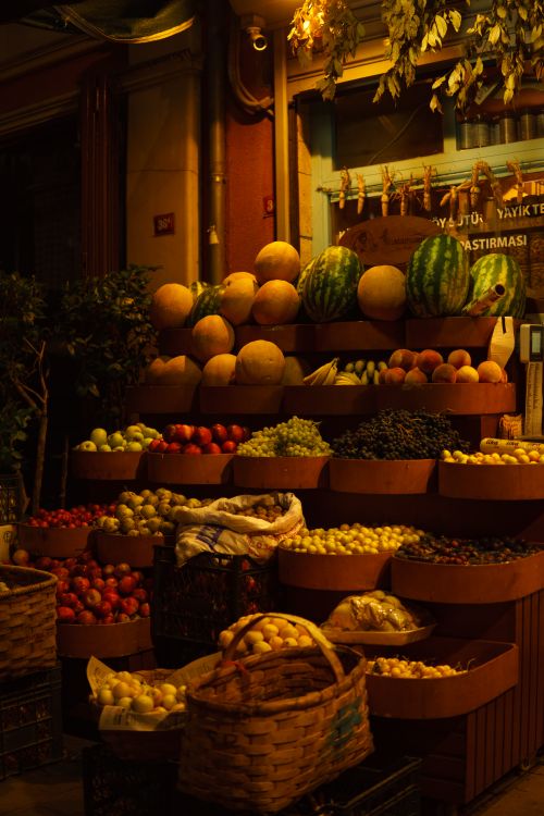 Free Vibrant night market stall displaying assorted fresh fruits and vegetables with warm lighting. Stock Photo