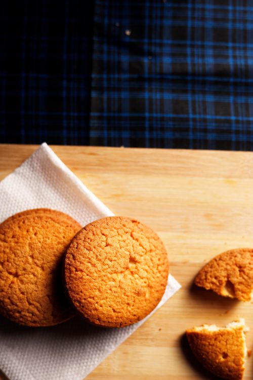 Free Close-up of freshly baked golden cookies arranged on a wooden board, offering a warm and delicious look. Stock Photo
