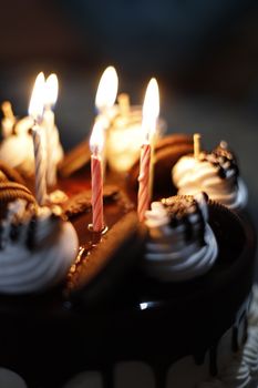 Close-up of a chocolate cake with decorative cream and lit candles, ideal for celebrations.