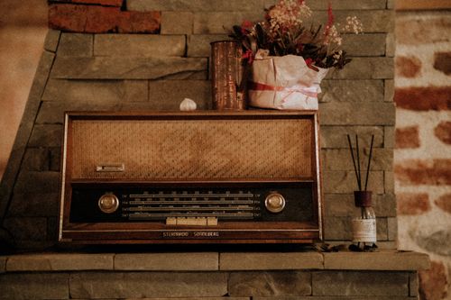 Free A classic vintage radio placed on a stone fireplace mantel with decorative flowers and aroma diffuser. Stock Photo