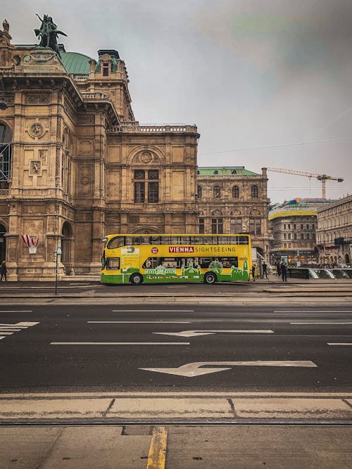Yellow and Green Bus on Road Near Brown Concrete Building