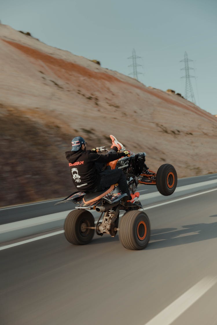 A Man Riding Black And Red ATV On The Road