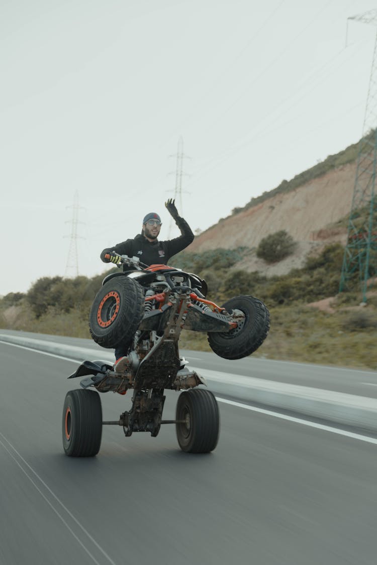 A Man Riding On Black ATV On The Road