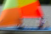 Artistic blur of a vibrant sailboat in motion on a serene lake, capturing dynamic colors and movement.