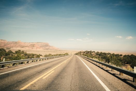 A scenic view of an open road in Arizona with a blue sky and desert landscape.
