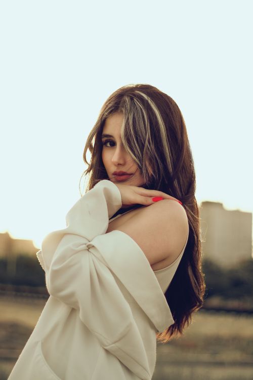 Free Elegant portrait of a fashion-forward young woman posing outdoors during sunset, showcasing a chic style. Stock Photo