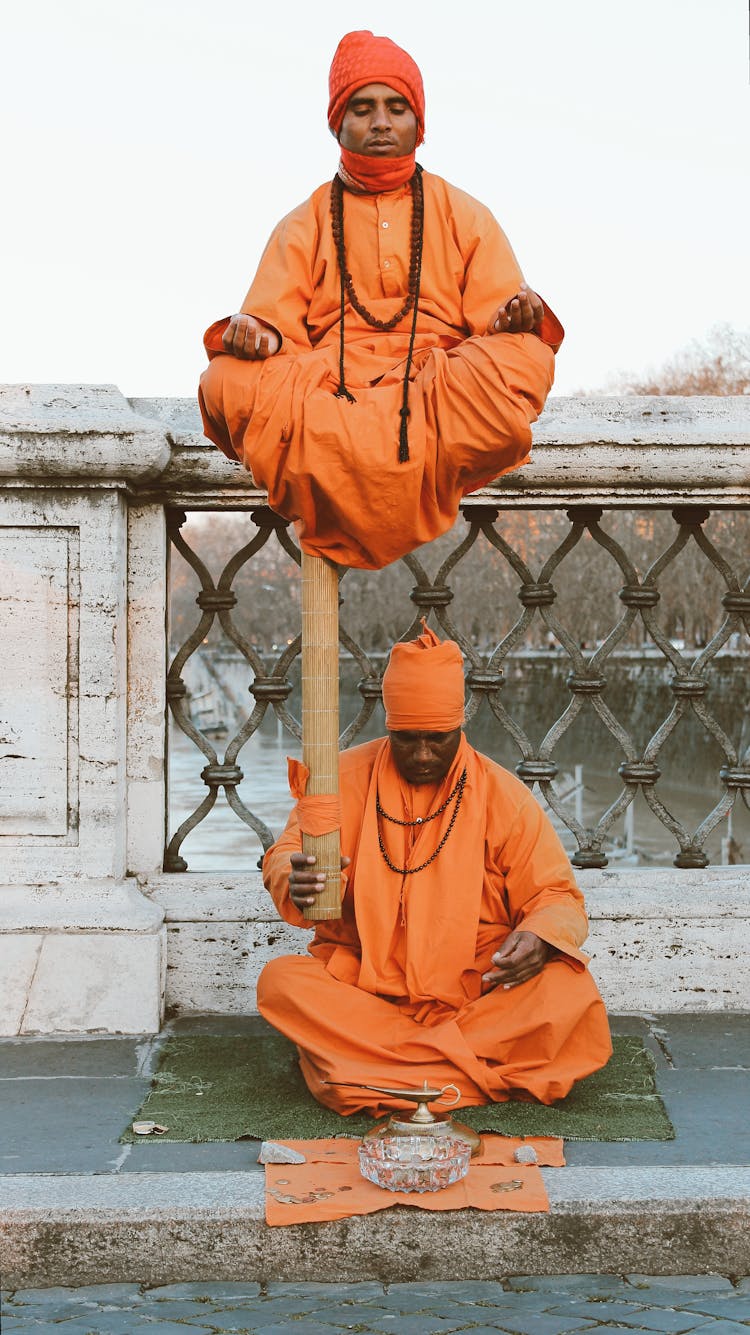 Man In Orange Thobe Sitting On Brown Plastic Seat