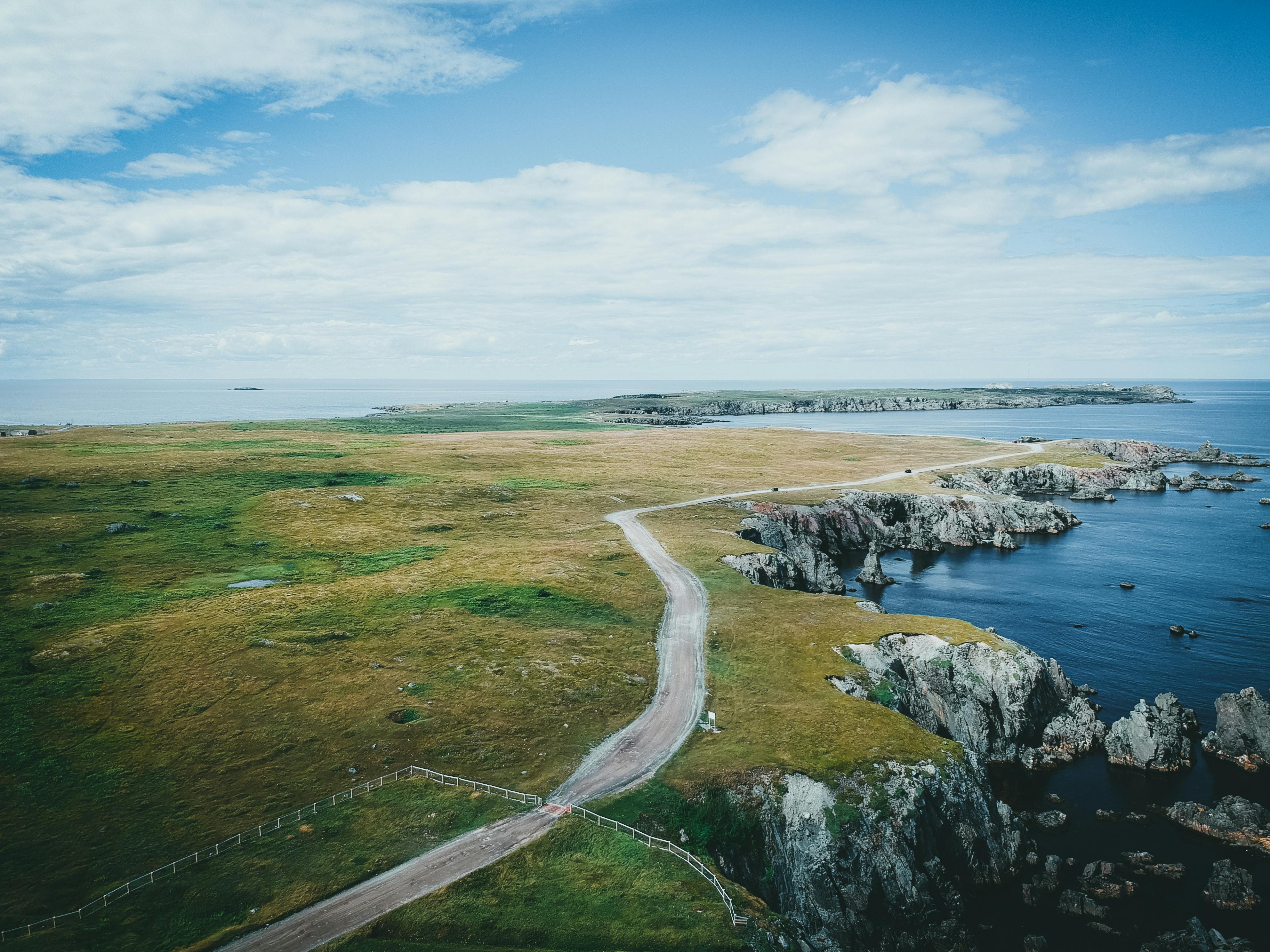 Scenic aerial view of a rugged coastal landscape with rocky cliffs and winding road.