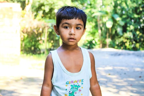Boy in White Tank Top Standing on Focus Photo