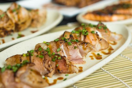 Free Delicious grilled chicken rolls garnished with fresh chives on a ceramic plate. Stock Photo