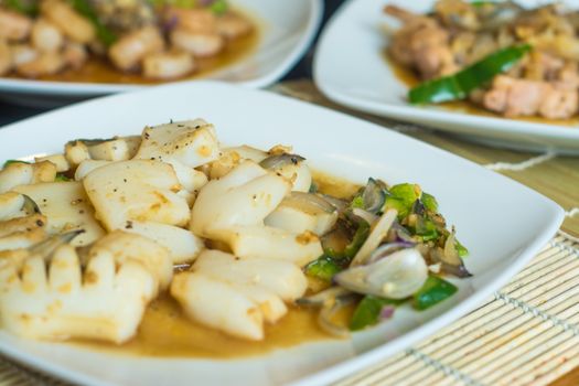 A deliciously plated squid dish with vegetables on a white plate, perfect for gourmet dining.