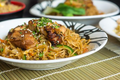 Free Close-up of delicious Asian-style noodles with grilled chicken and vegetables on a bamboo mat. Stock Photo