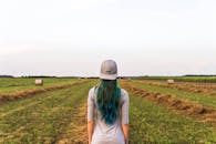 乡间田野里，一个女孩站在广阔的天空下，身旁堆着干草