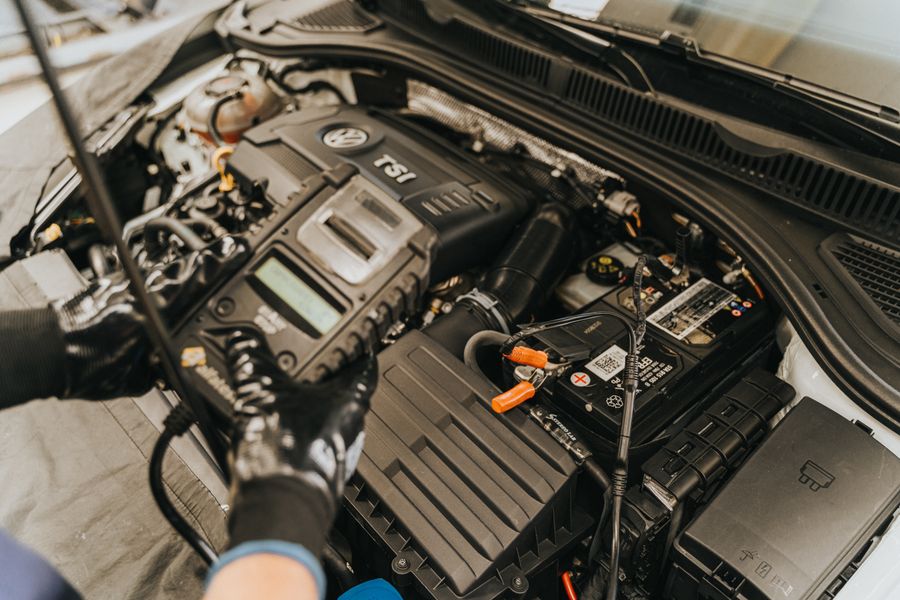 Gloved hands working at the battery in an open engine bay
