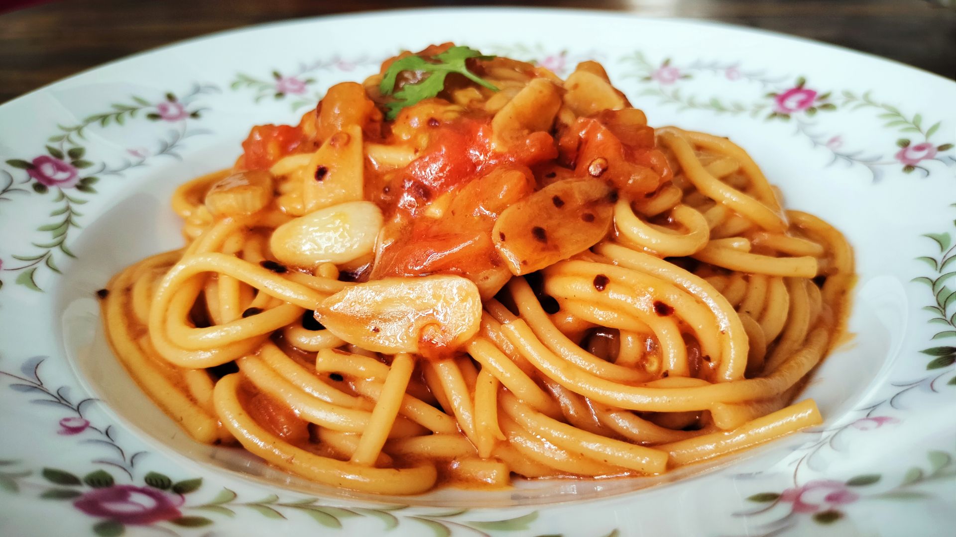 Delicious plate of spaghetti topped with rich tomato and garlic sauce, served on a decorative dish.