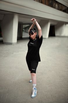 Young woman in black sporty outfit posing confidently in an urban setting.