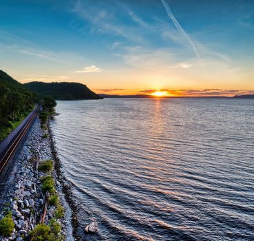 Beautiful sunset over Maple Springs, MN, with a shoreline and railway in view.