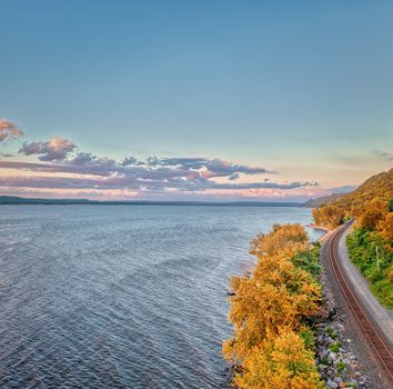 Scenic aerial view of a railway along a vast lake with vibrant autumn trees in Maple Springs, Minnesota.