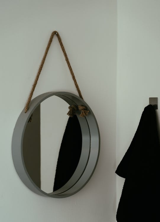 Round Mirror Hanging on String on Wall