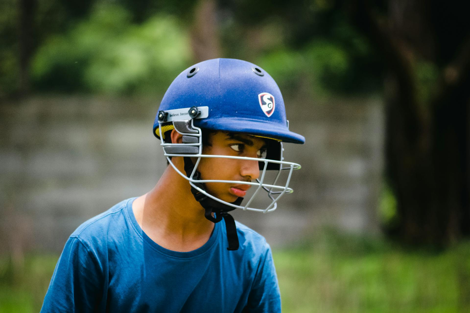 Portrait of a young cricketer wearing a helmet outdoors in Pune, India.