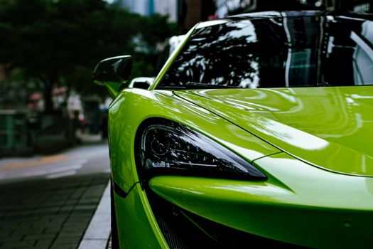 Detailed shot of a vibrant green sports car parked on an urban street, showcasing sleek design.