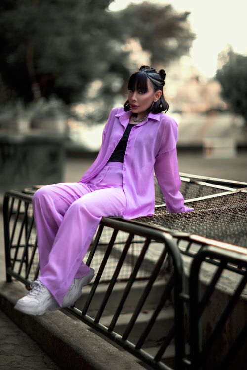 Free A fashionable woman in purple sitting outdoors on metal railings in Tehran. Stock Photo