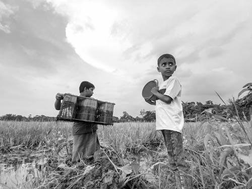 A Grayscale Photo of Young Boys Standing on Grass Field