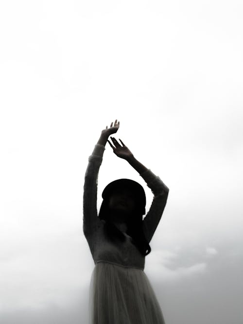 A Grayscale Photo of a Woman Raising Her Hands