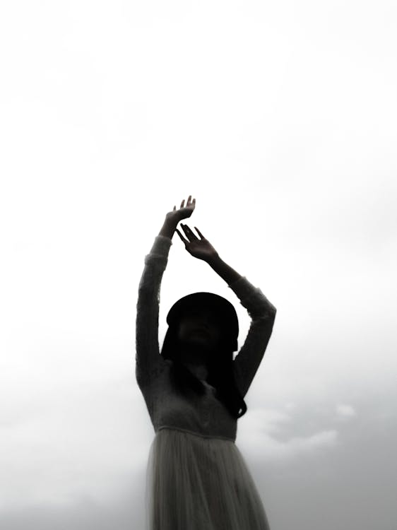 A Grayscale Photo of a Woman Raising Her Hands