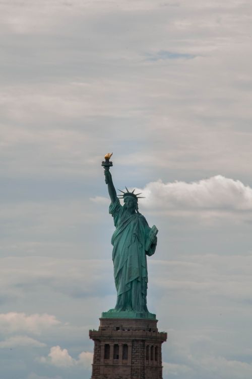 Free The Statue of Liberty stands tall against a cloudy sky in New York City, symbolizing freedom. Stock Photo
