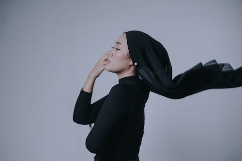 A Side View of a Woman in Black Long Sleeves with Her Hand on Her Face