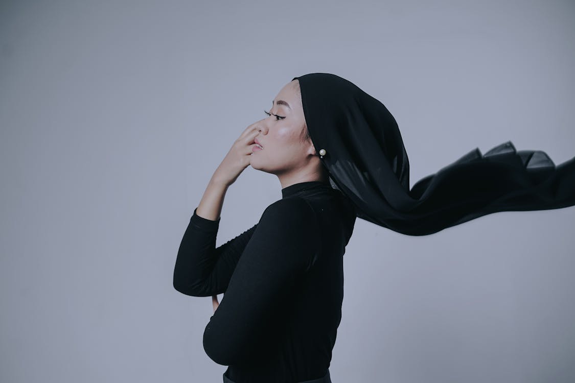 A Side View of a Woman in Black Long Sleeves with Her Hand on Her Face