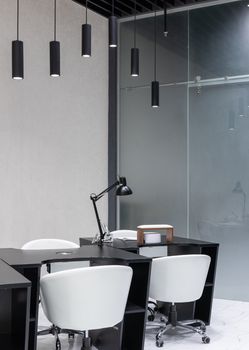 A sleek modern office interior featuring elegant black furniture and pendant lights.