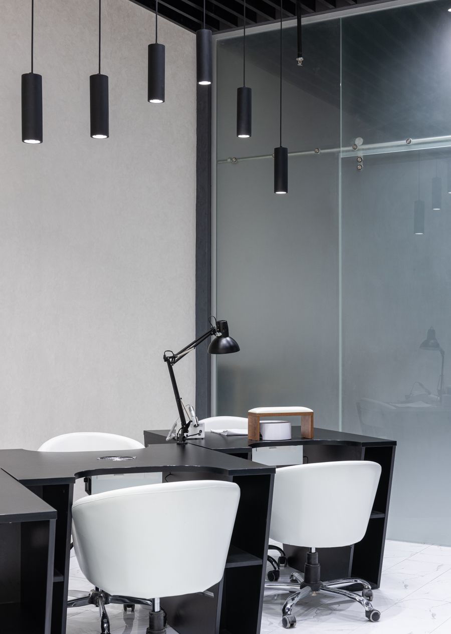 Dark toned office interior with black furniture and pendant lighting