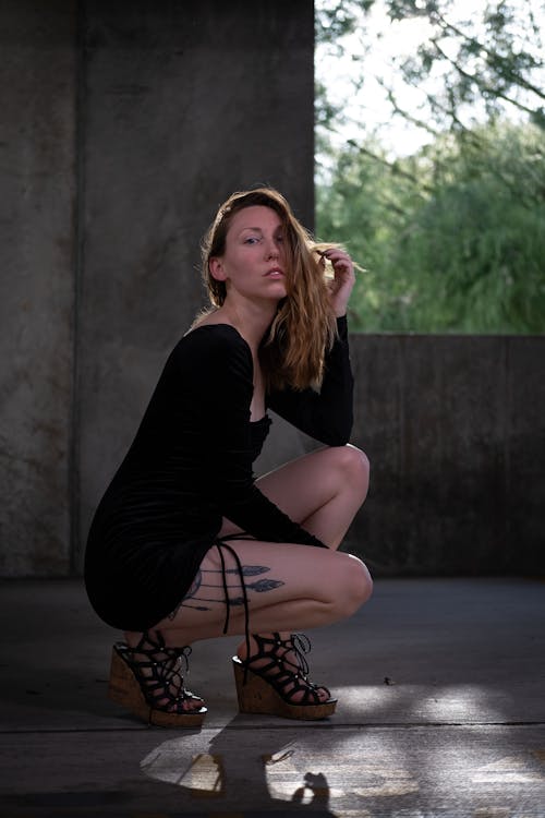 Free A Woman in Black Long Sleeve Dress Sitting while Posing Stock Photo