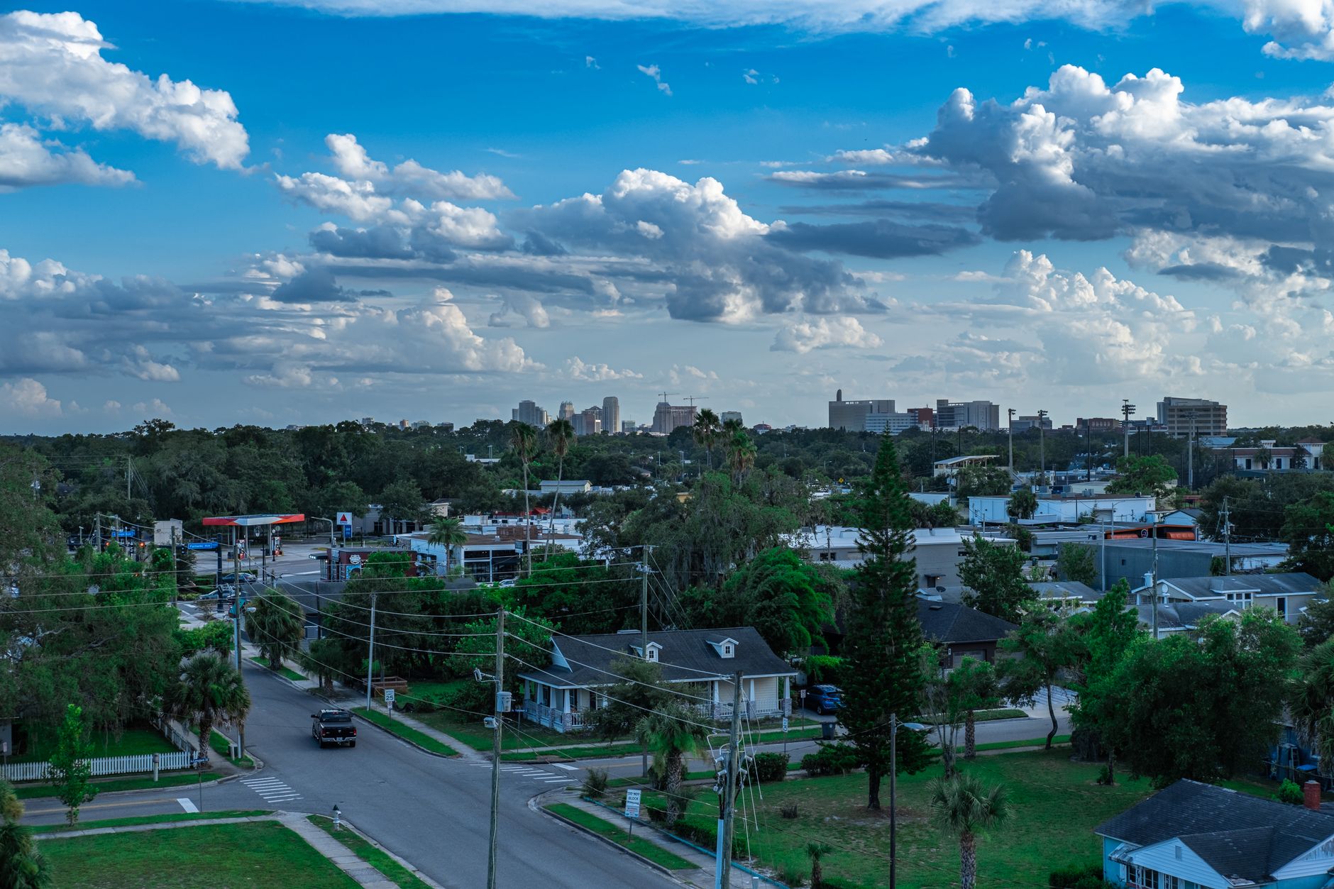 Aerial cityscape showcasing residential neighborhood with lush greenery and a vibrant blue sky.